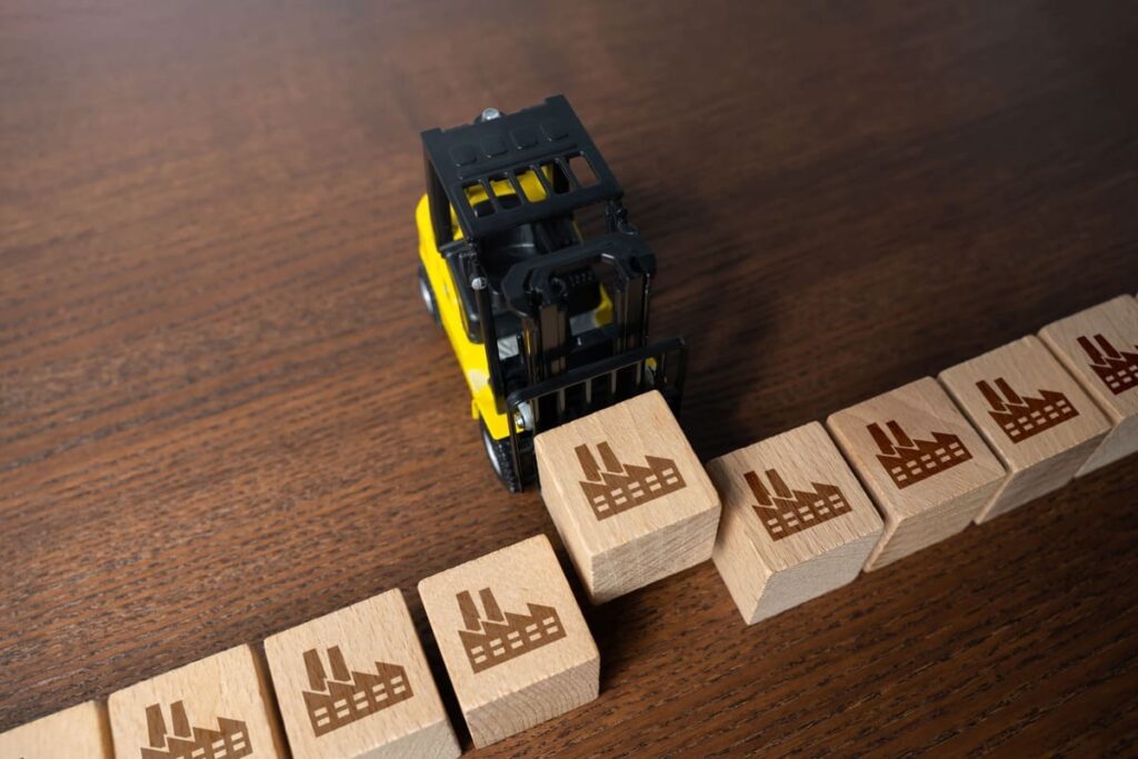 Stivuitor miniatural mutând cuburi cu simboluri industriale