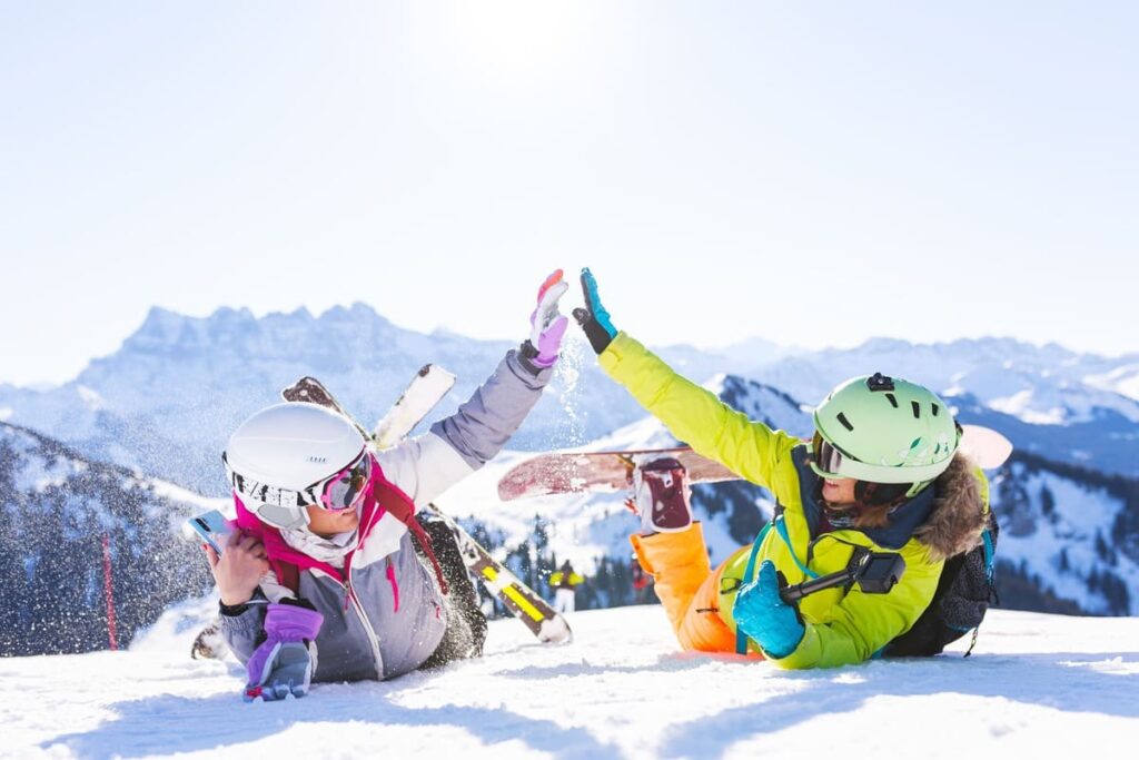 two snowboarders giving high five on snowy mountain
