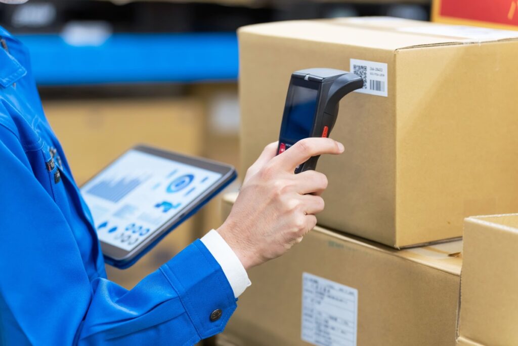 warehouse worker scanning parcel with barcode device and tracking dashboard on tablet